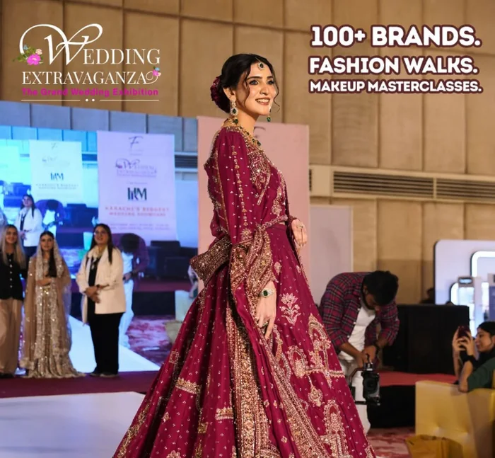 A model on the runway at Wedding Extravaganza, with exhibitor stalls, sponsor banners and a seated audience behind her