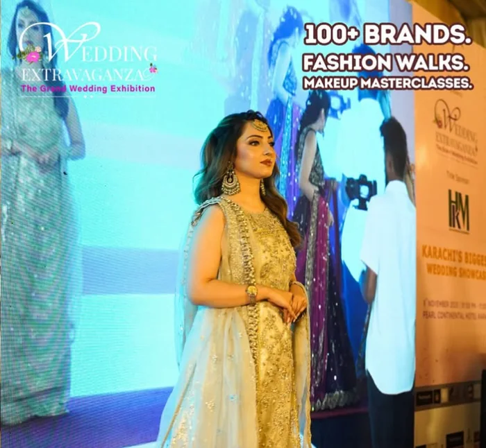 A model on stage at Wedding Extravaganza in front of the event SMD screen and a title sponsor banner